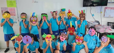 Grupo de niños con camisas azules sosteniendo máscaras de animales coloridas