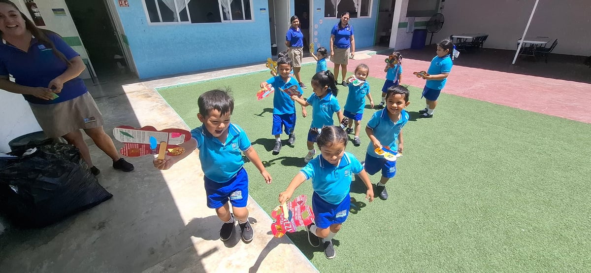 Grupo de niños con uniformes azules jugando en el patio de recreo