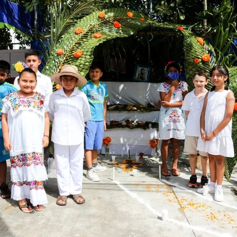 Grupo de niños frente a altar decorado con flores naranjas