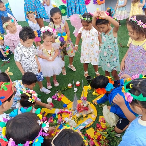 Niños pequeños jugando con/manualidades de flores en el pasto